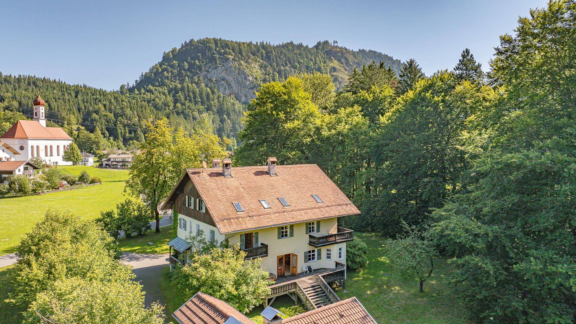 Luftaufnahme des Hauses mit Satteldach, umgeben von Wald und mit Blick auf die Hügellandschaft.