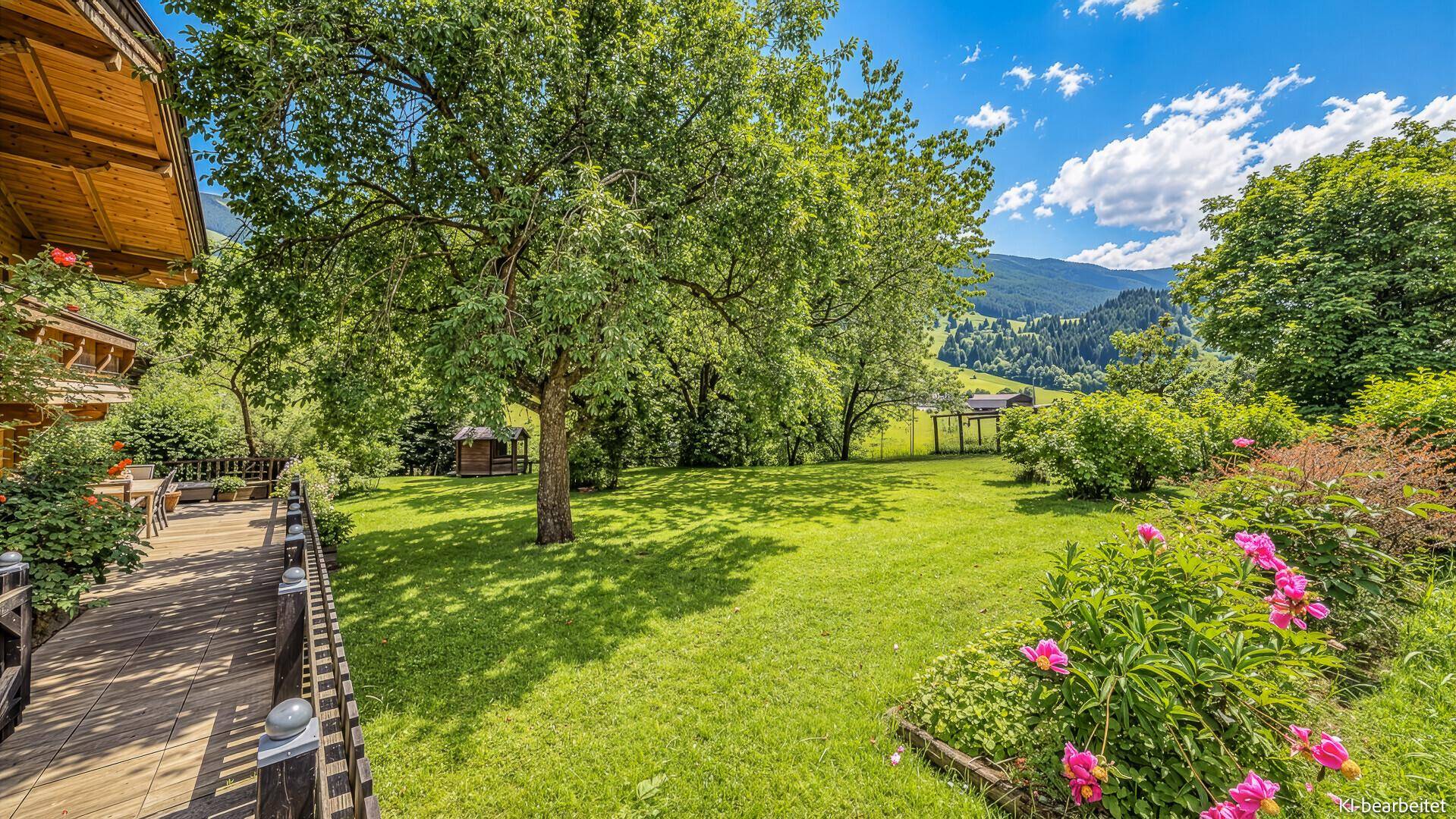 Großer grüner Garten mit altem Baum, Blumenbeeten und Panoramablick auf die Landschaft.