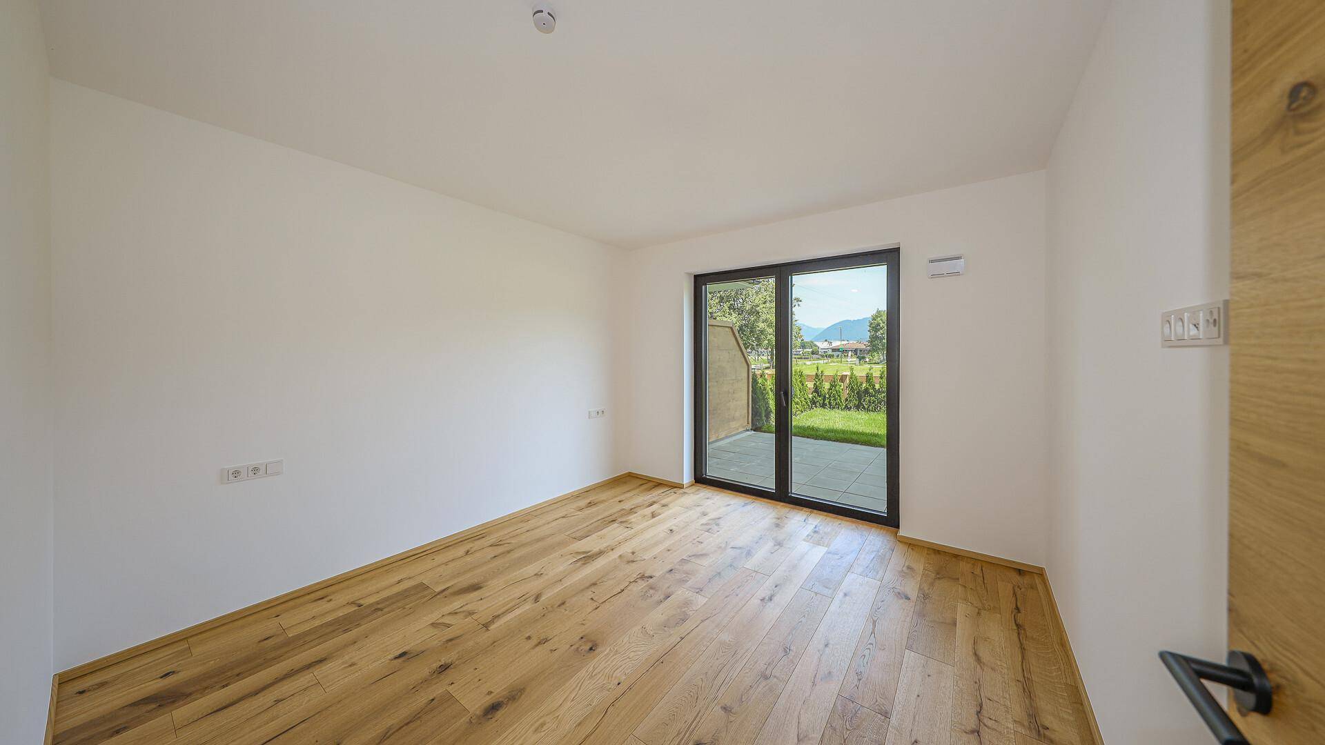 Helles Schlafzimmer mit Holzboden und Zugang zu einer privaten Terrasse oder Gartenbereich.