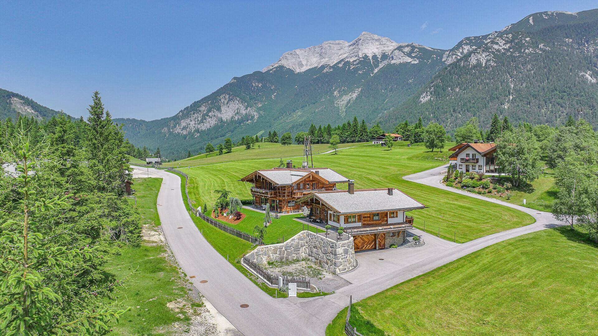 Weitläufige Ansicht von zwei Chalets in einer idyllischen Berglandschaft mit grünen Wiesen.