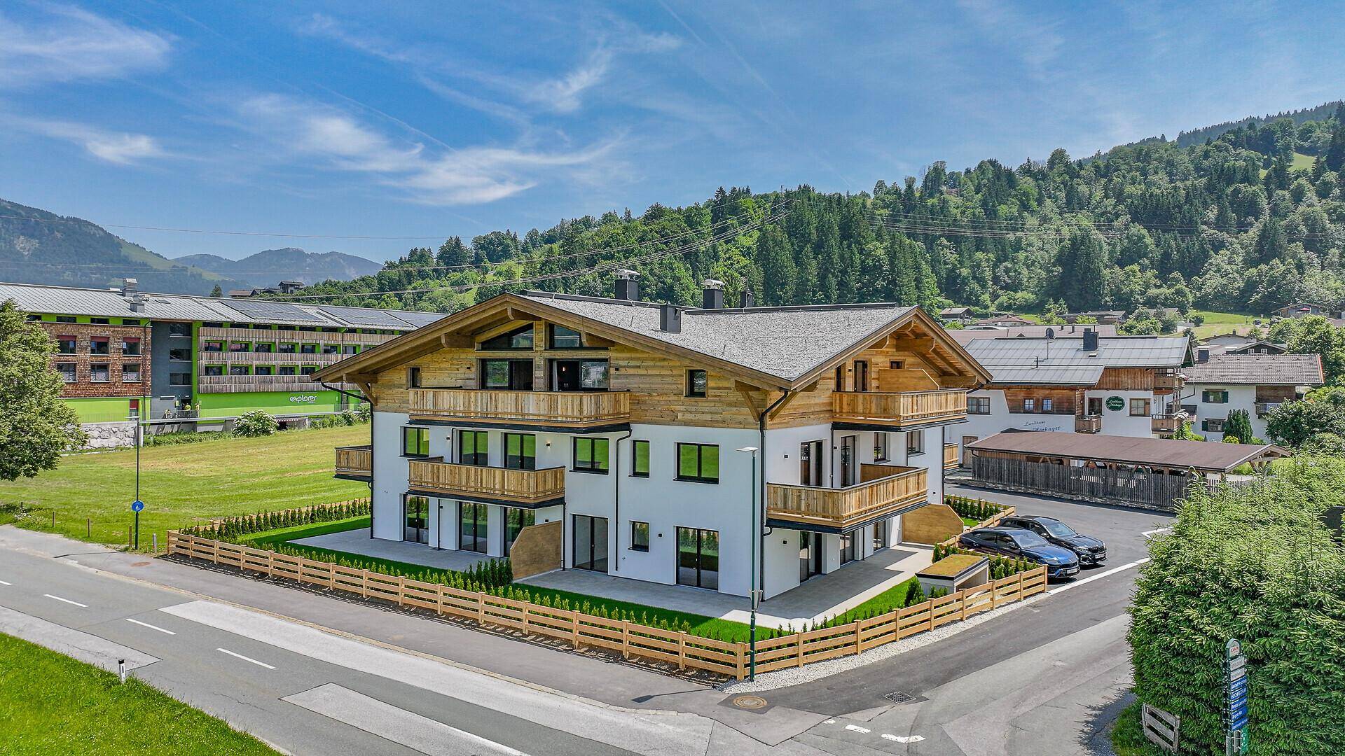 Modernes Wohngebäude im alpinen Stil mit Balkonen und umliegender Natur.