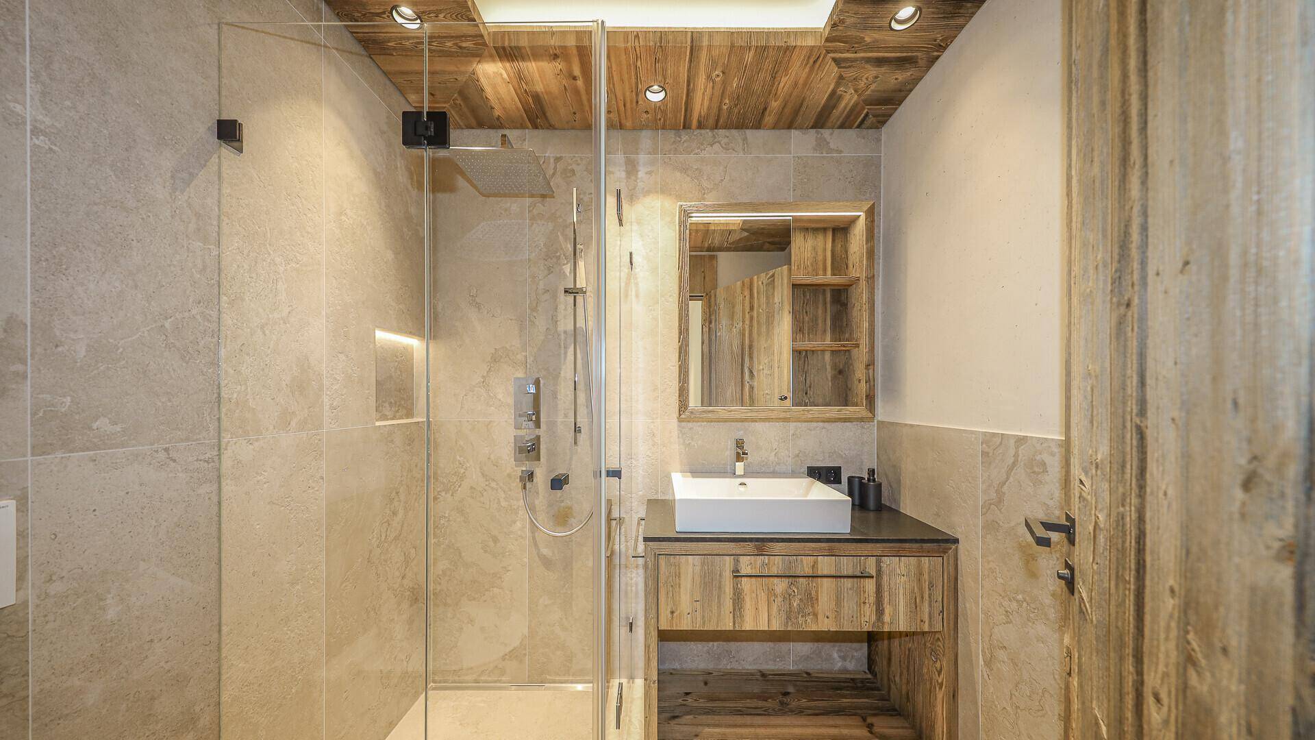 Modernes Badezimmer mit Einzelwaschbecken, begehbarer Dusche und Holzverkleidung.