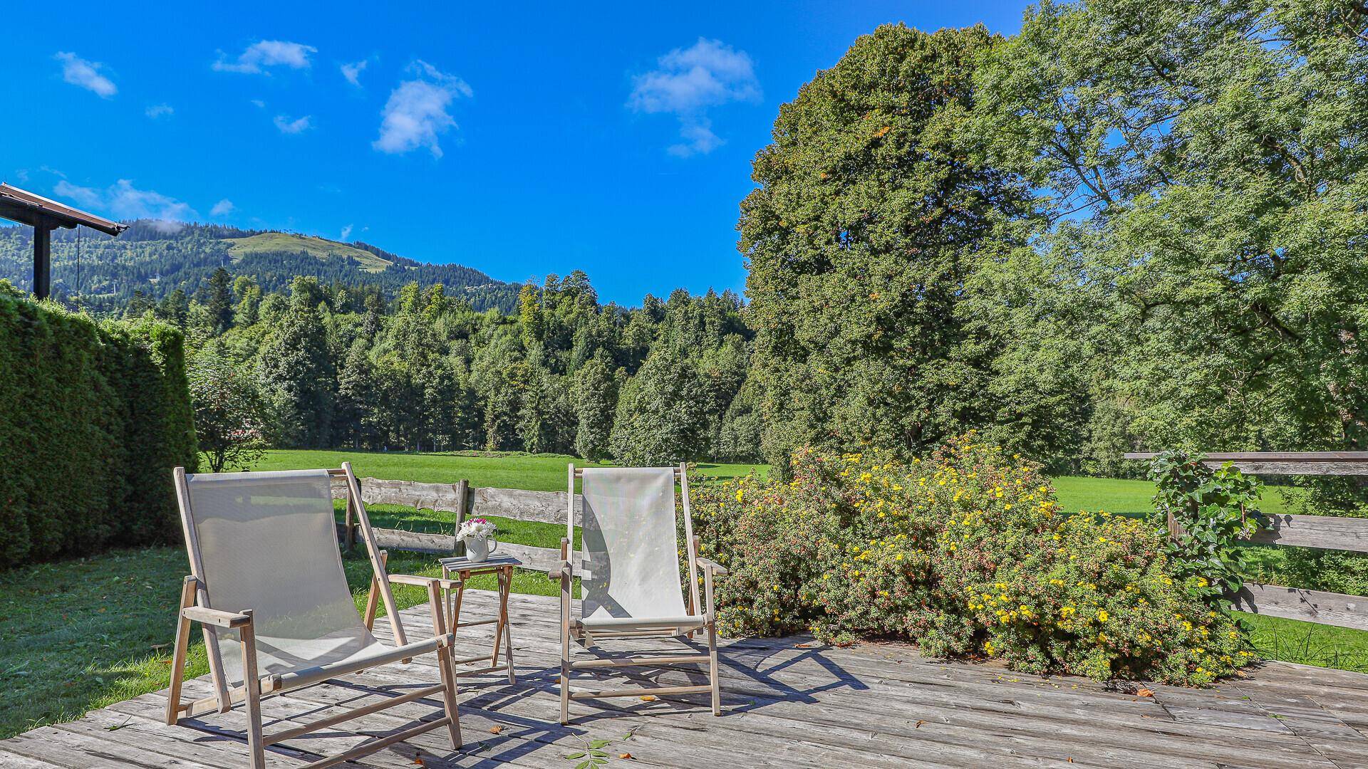 Sonniger Terrassenbereich mit Liegestühlen und weitem Blick auf die grüne Landschaft.