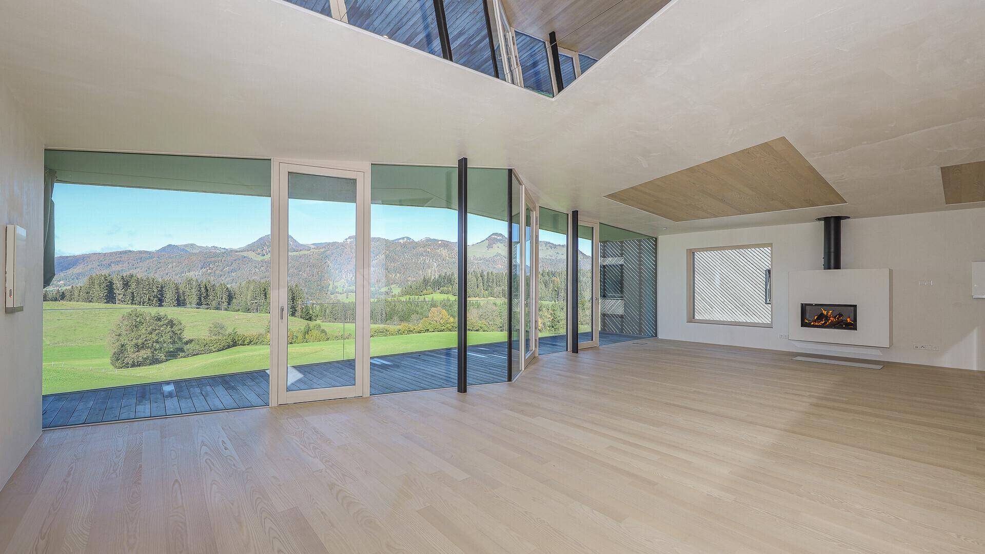Geräumiger, unmöblierter Wohnbereich mit großen Fensterfronten und beeindruckendem Bergblick.
