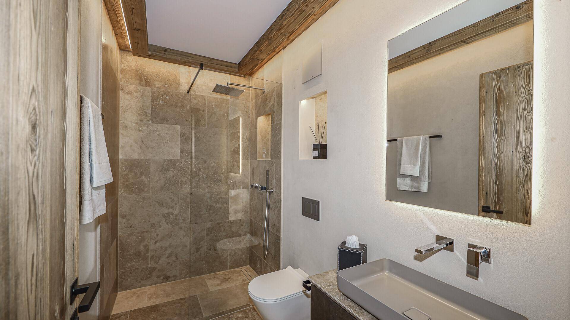 Modernes Badezimmer mit begehbarer Dusche, Natursteinfliesen und Holzverkleidung.