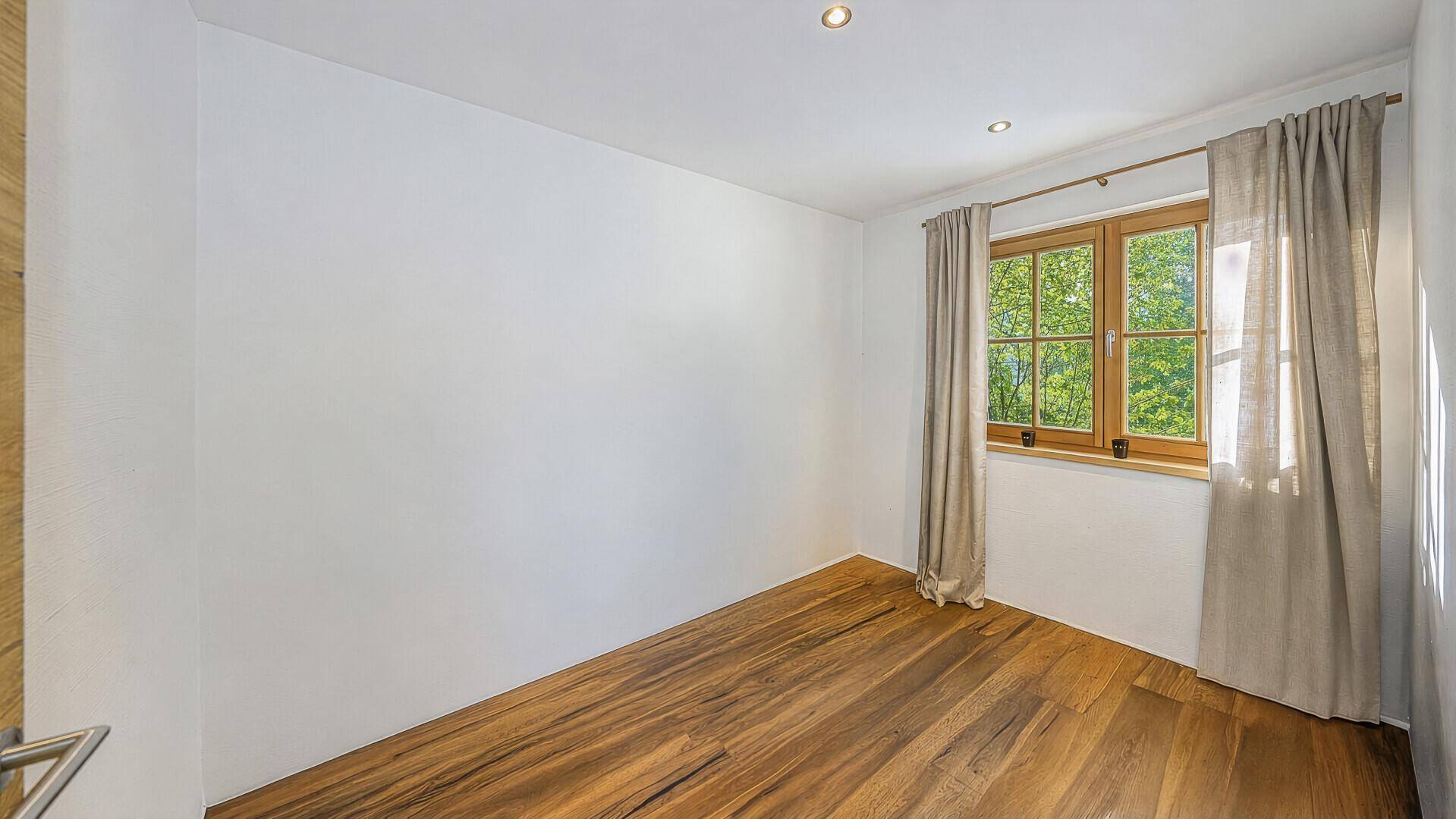 Helles Zimmer mit Holzboden und Fenster, ideal als Schlaf- oder Gästezimmer.