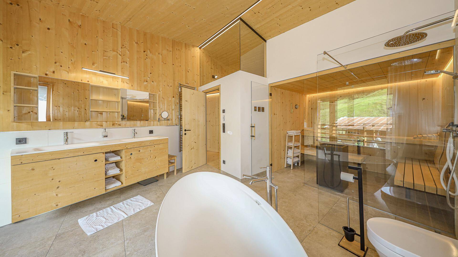 Luxuriöses Badezimmer mit freistehender Badewanne, großer Dusche, Sauna und Doppelwaschbecken.