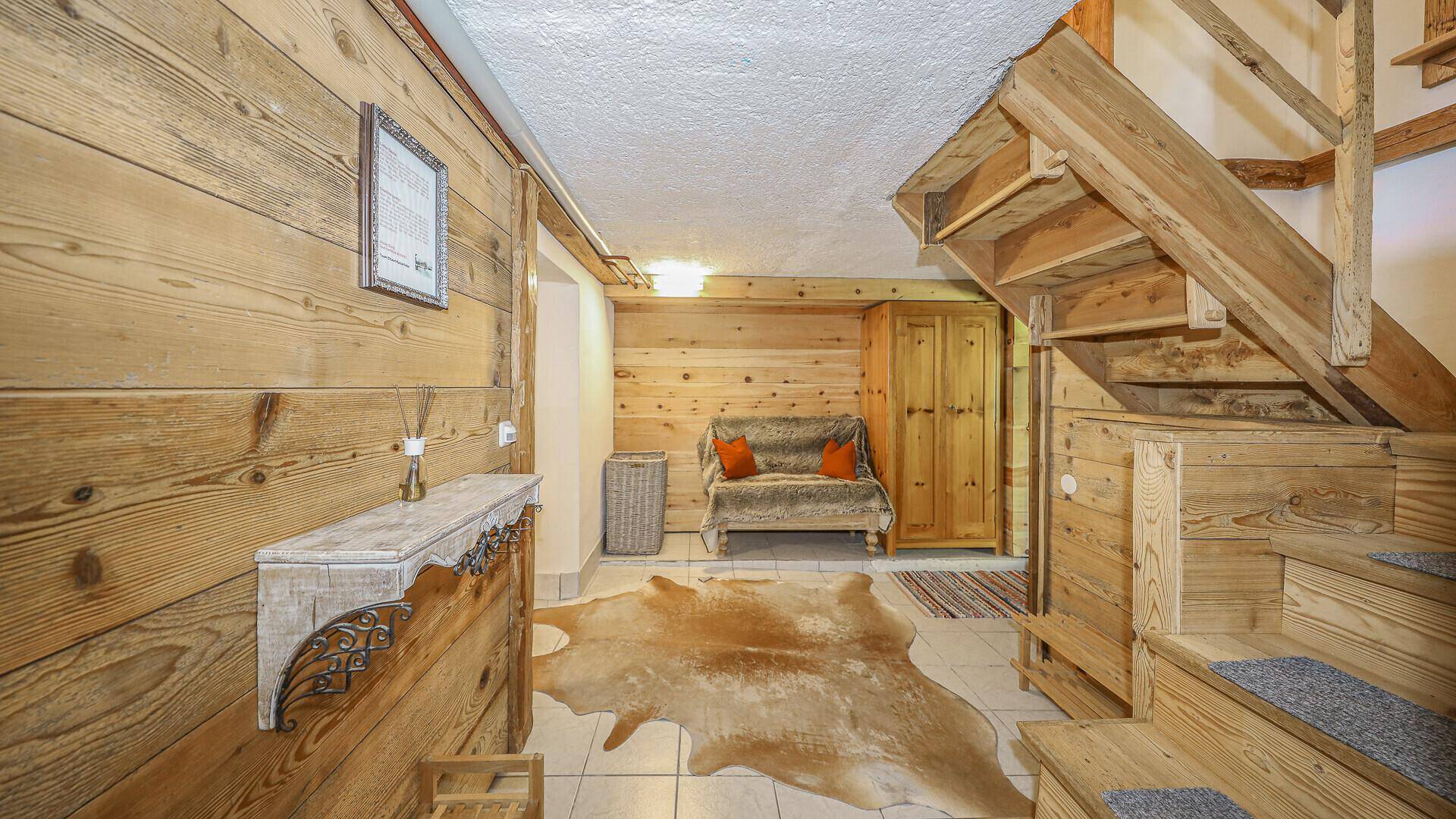 Rustikaler Kellerraum mit Holzvertäfelung, Fliesenboden und Sitzgelegenheit.