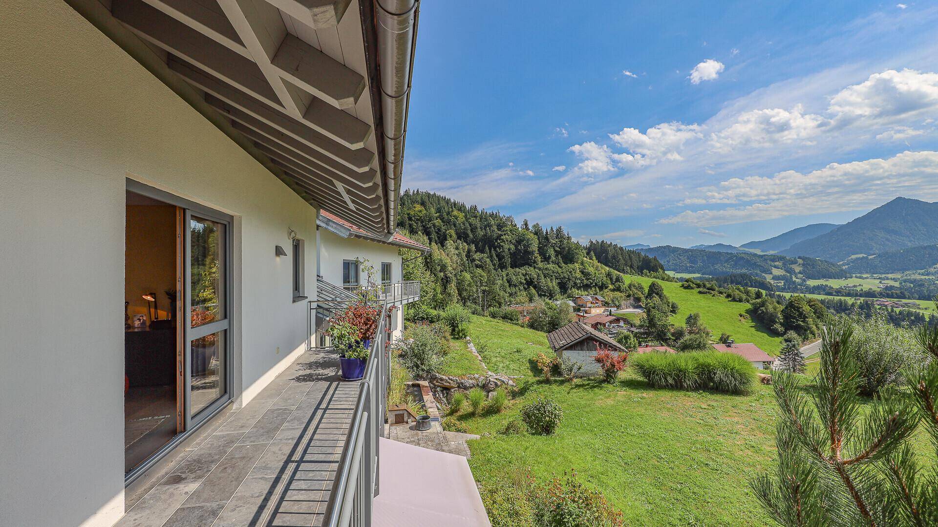 Langer Balkon mit Geländer und weitem Blick auf die grüne Hügellandschaft und Berge.