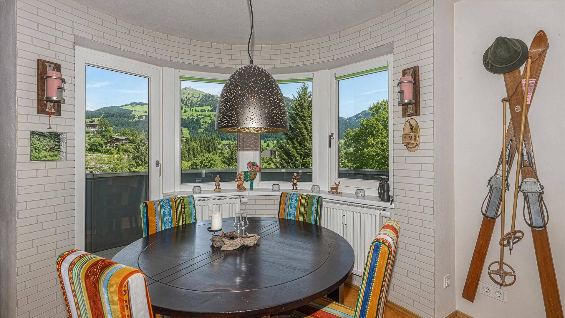 Heller Essbereich mit runden Fenstern und Panoramablick auf die umliegenden Berge.