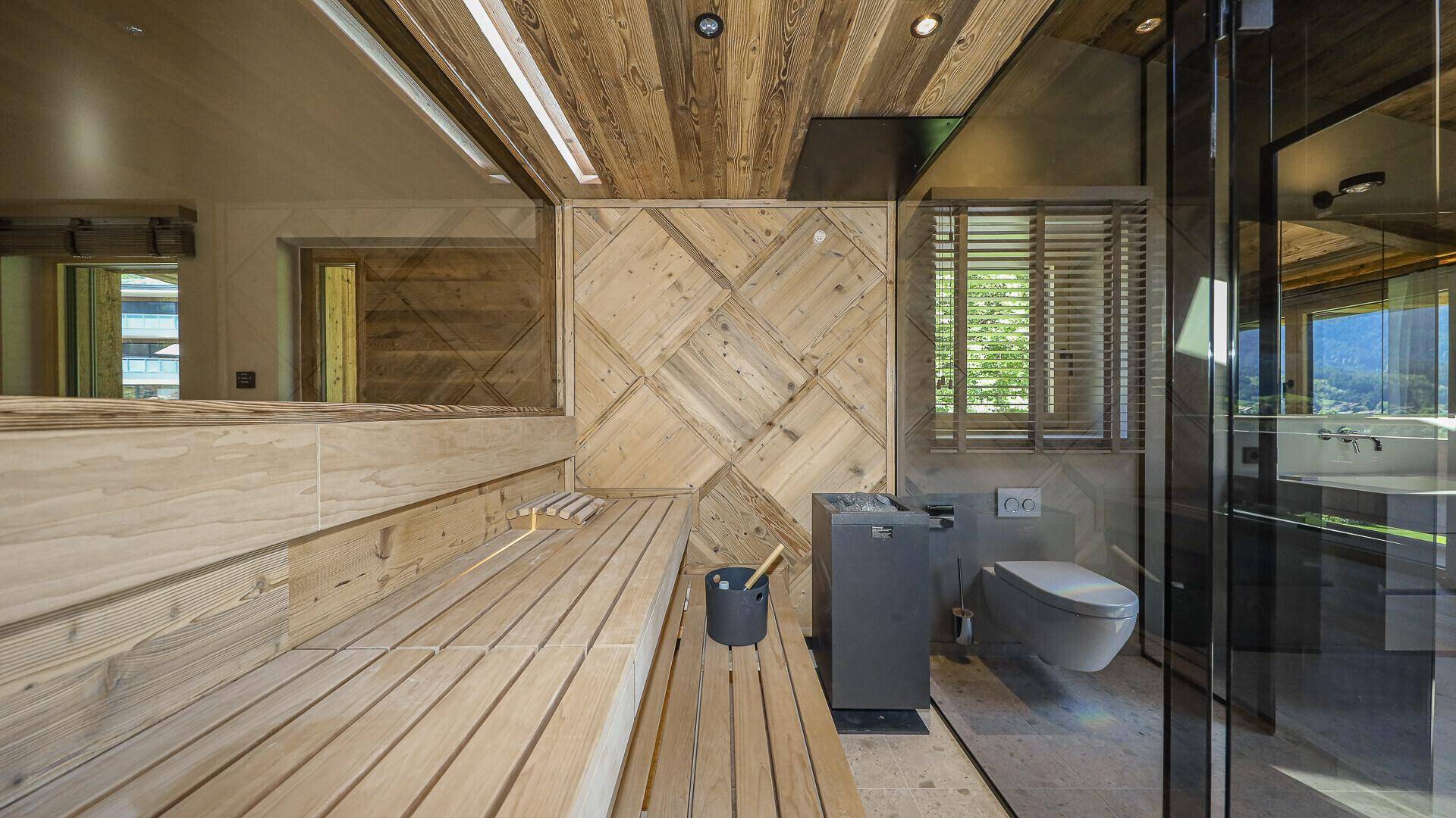 Moderne Sauna mit Holzbänken und Heizofen, integriert in ein luxuriöses Badezimmer.