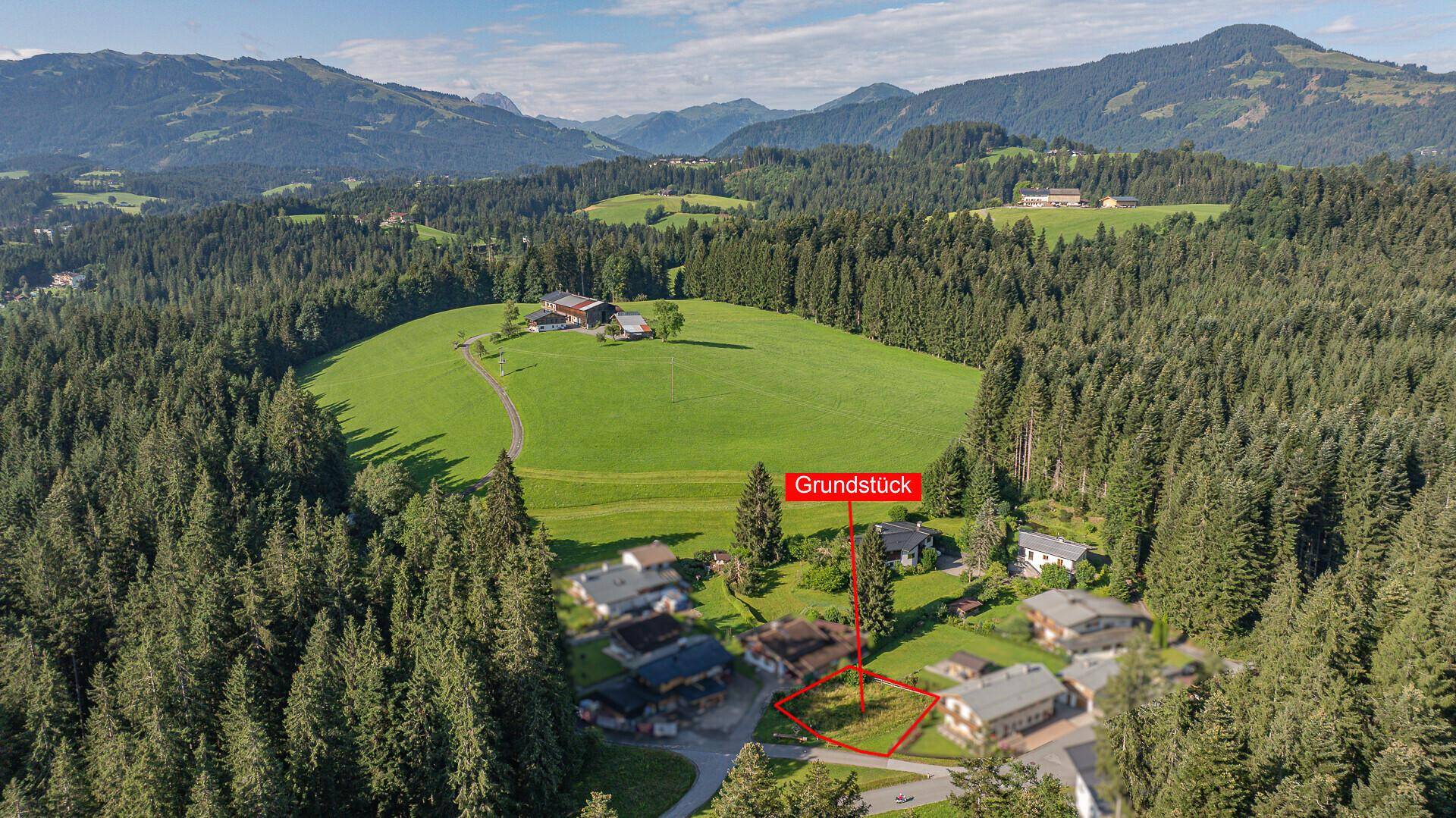 Übersicht des Grundstücks aus der Vogelperspektive, eingebettet in grüne Hügel und Wälder.