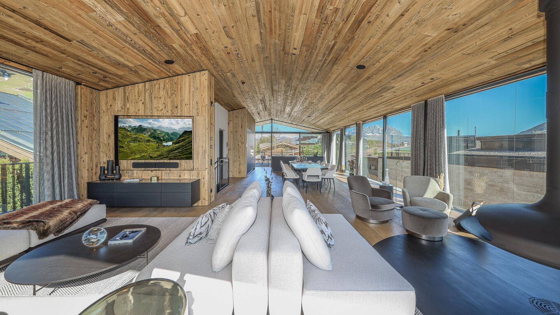 Großzügiger Wohn- und Essbereich mit Holzbalkendecke, Panoramafenstern und modernem Interieur.