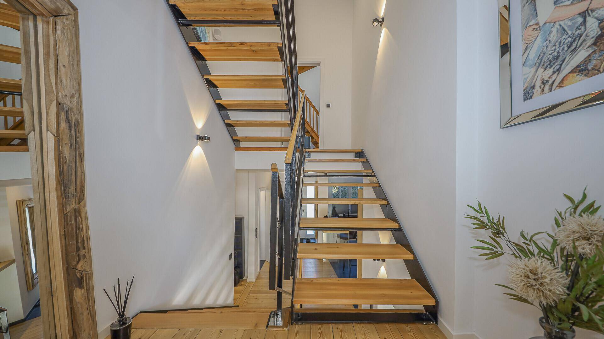 Elegante Holztreppe mit Metallgeländer, die die verschiedenen Ebenen des Hauses stilvoll verbindet.