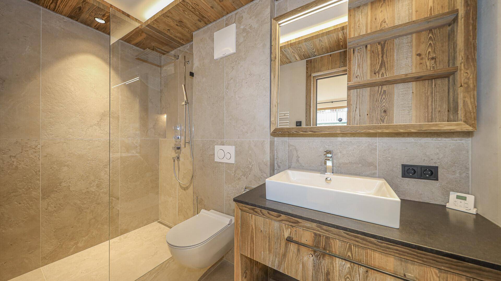 Modernes Badezimmer mit Einzelwaschbecken, wandhängendem WC und begehbarer Dusche.