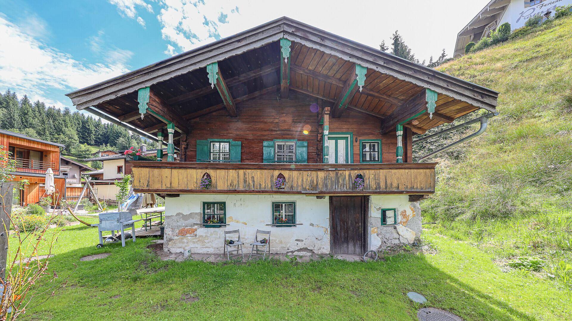 Traditionelles Holzhaus mit grün gestrichenen Fensterläden und blühendem Balkon.