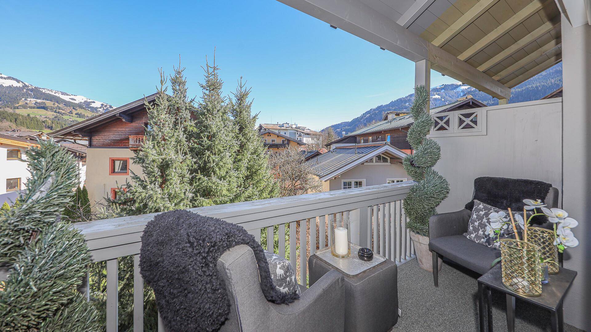 Gemütlicher Balkon mit Sitzgelegenheiten und weitem Blick auf die Berge und grüne Umgebung.