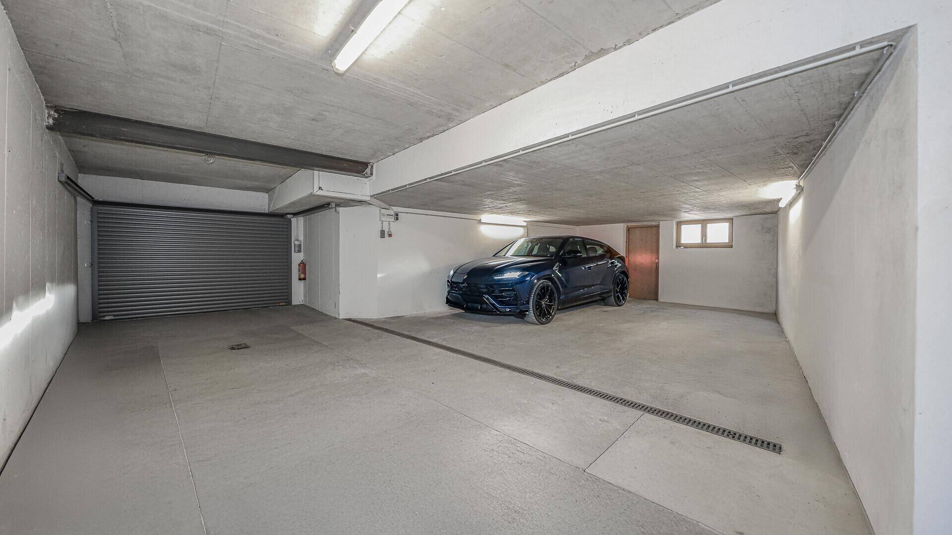 Geräumige Tiefgarage mit Betonboden und einem geparkten Luxusfahrzeug.