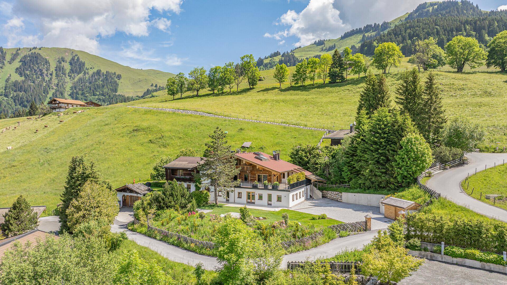 Idyllisches Chalet in alpiner Landschaft mit grünen Hügeln und sonnigem Wetter.