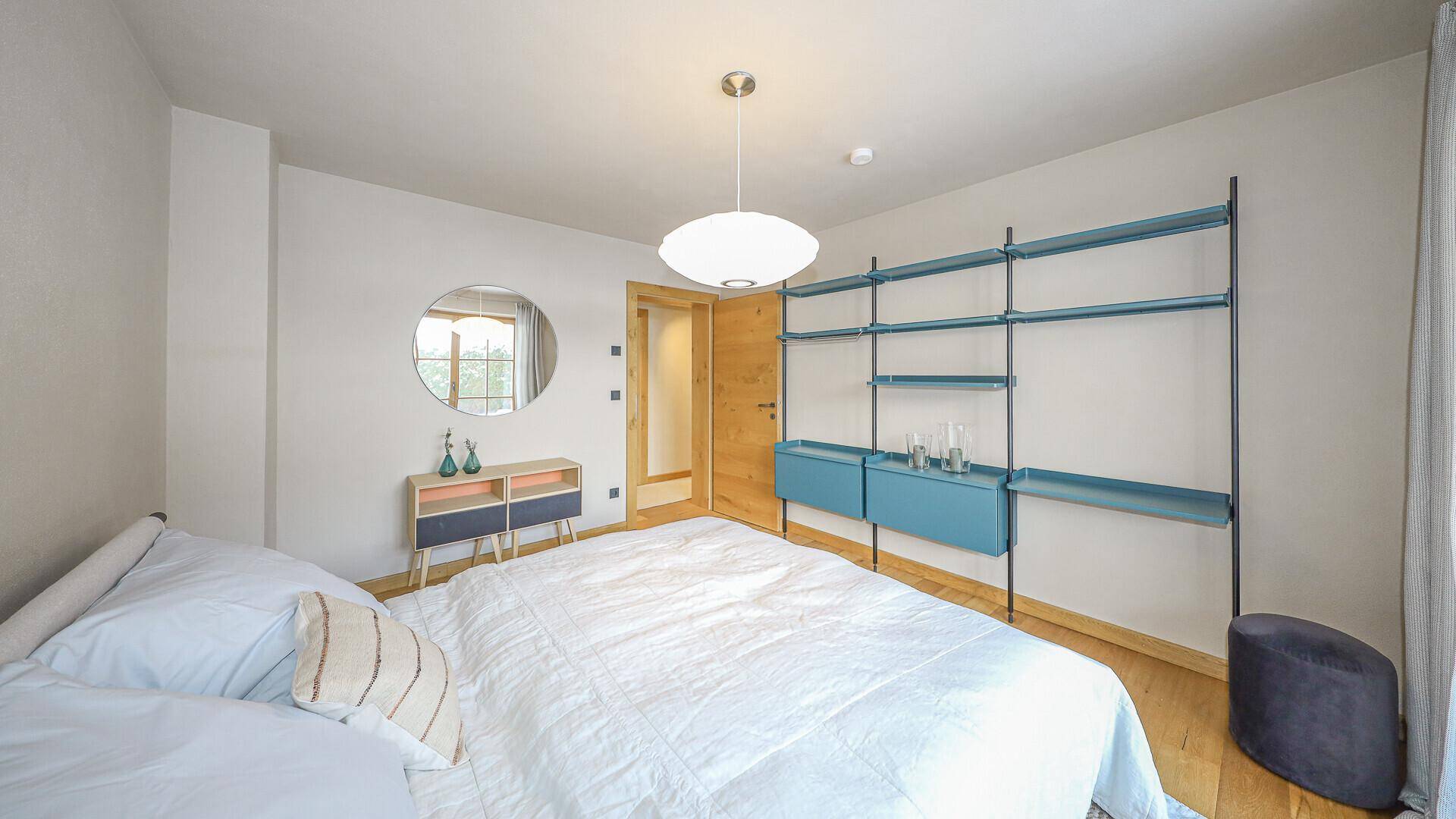 Modernes Schlafzimmer mit Holzboden, Doppelbett und stilvollem Regal an der Wand.