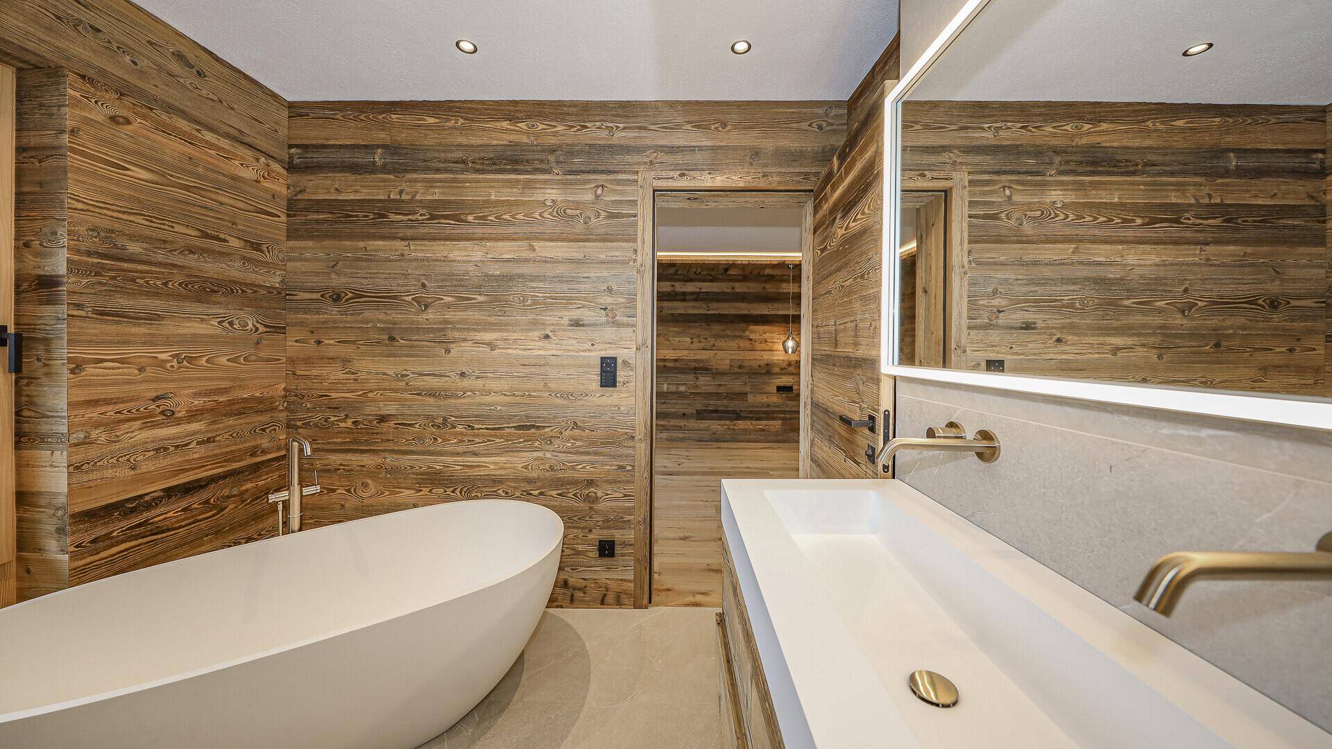 Elegantes Badezimmer mit freistehender Badewanne, Waschtisch und Holzwänden.