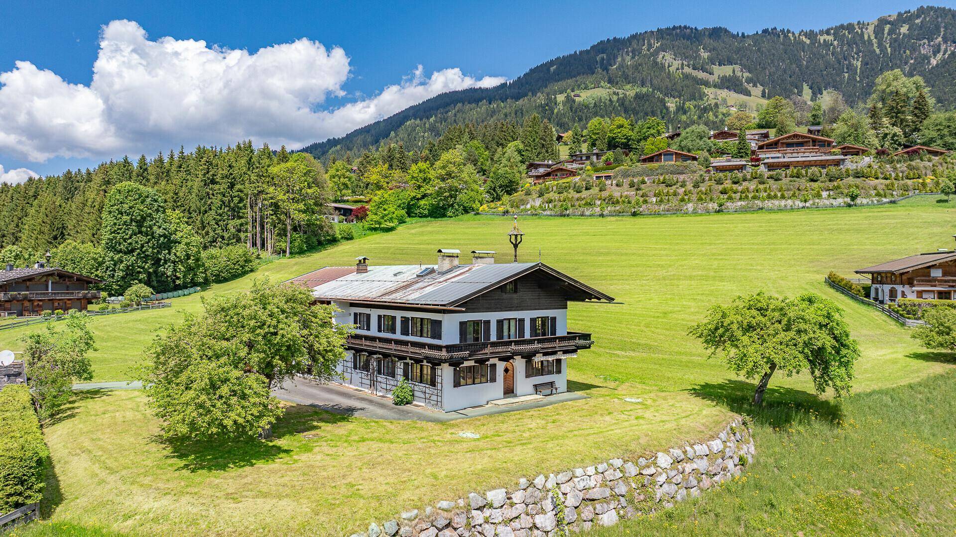 Traditionelles Haus in sonniger Hanglage mit weitem Blick über die grüne Landschaft.