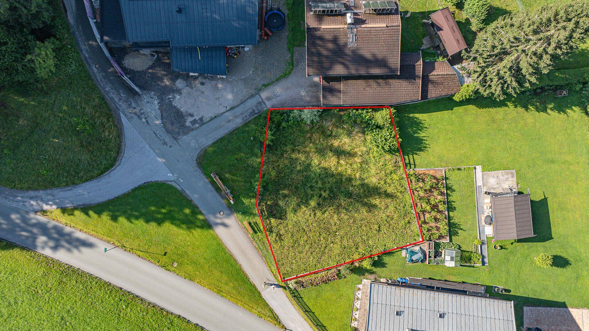 Draufsicht auf ein umrandetes Baugrundstück mit angrenzenden Straßen und Häusern.