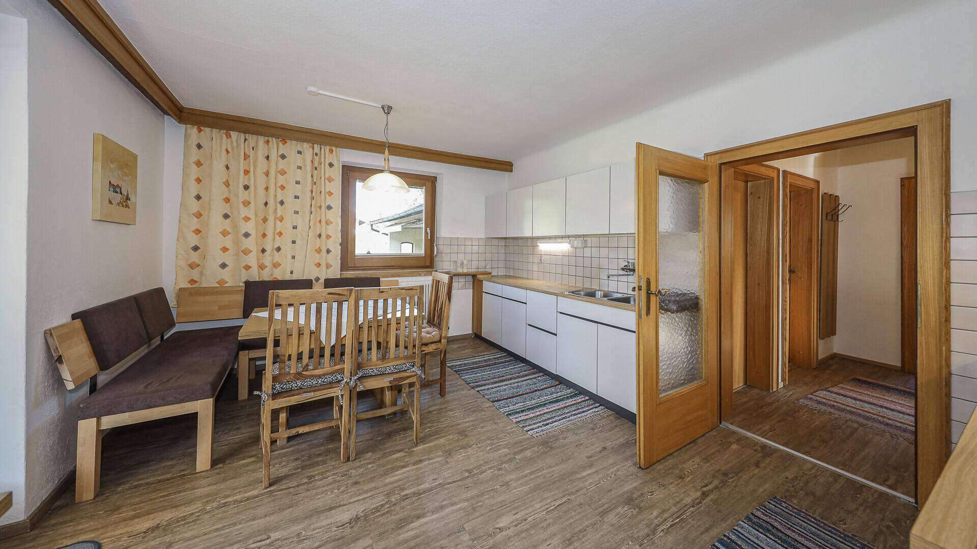 Traditionelle Küche mit Essbereich, weißen Schränken, Holzmöbeln und Blick ins Grüne.