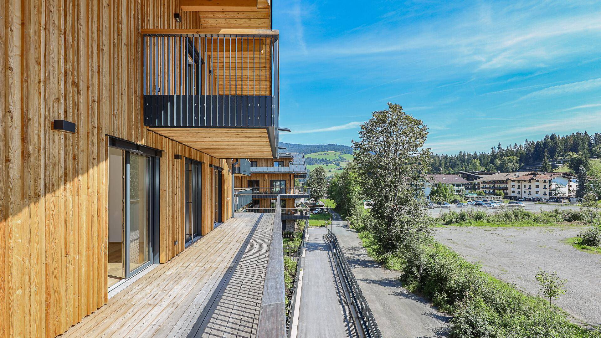 Langer Holzbalkon mit Blick auf die grüne Umgebung und einen Weg.