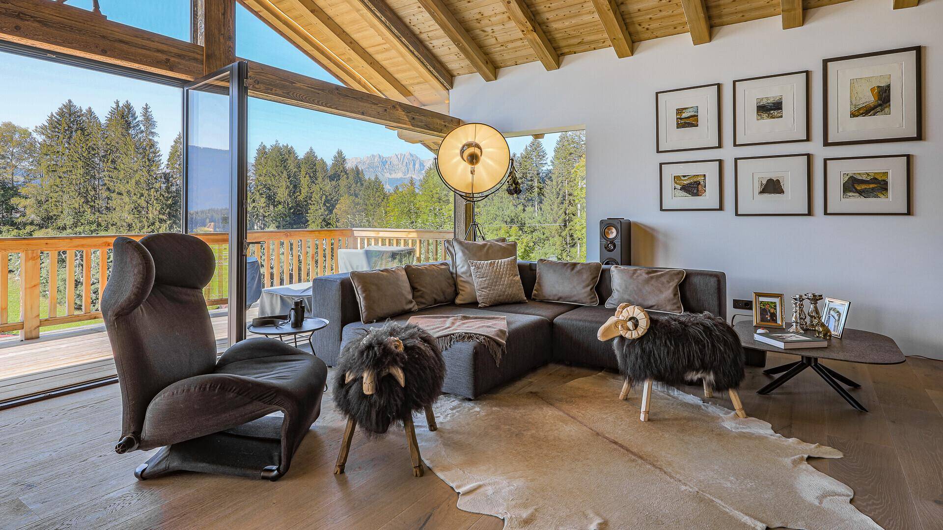 Stilvolles Wohnzimmer mit bequemer Sitzecke, Holzboden und beeindruckendem Bergblick durch große Fenster.