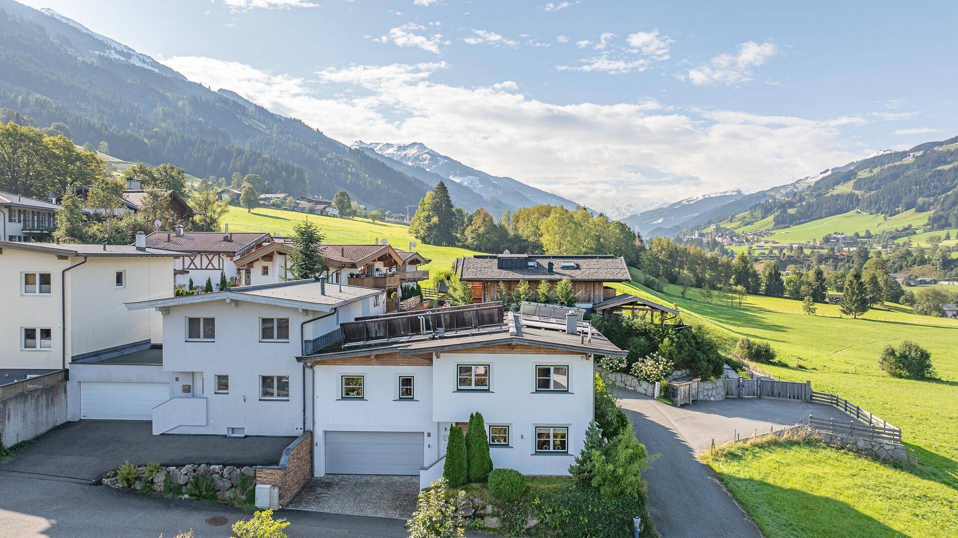 Weitläufige Ansicht einer Wohnsiedlung in alpiner Landschaft mit sonnigen Hängen.