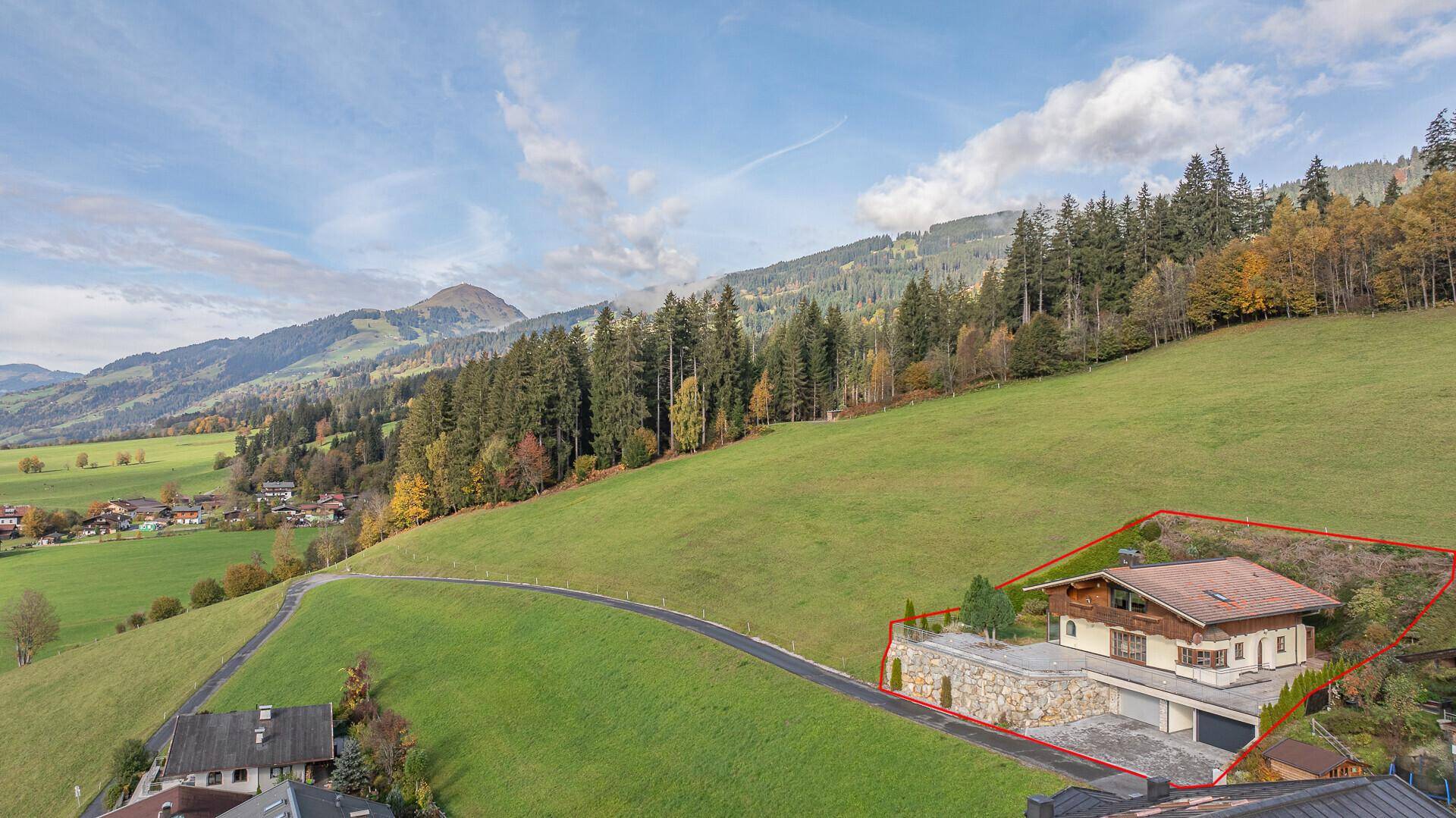 Luftaufnahme des Anwesens mit markiertem Grundstück in einer malerischen Berglandschaft.