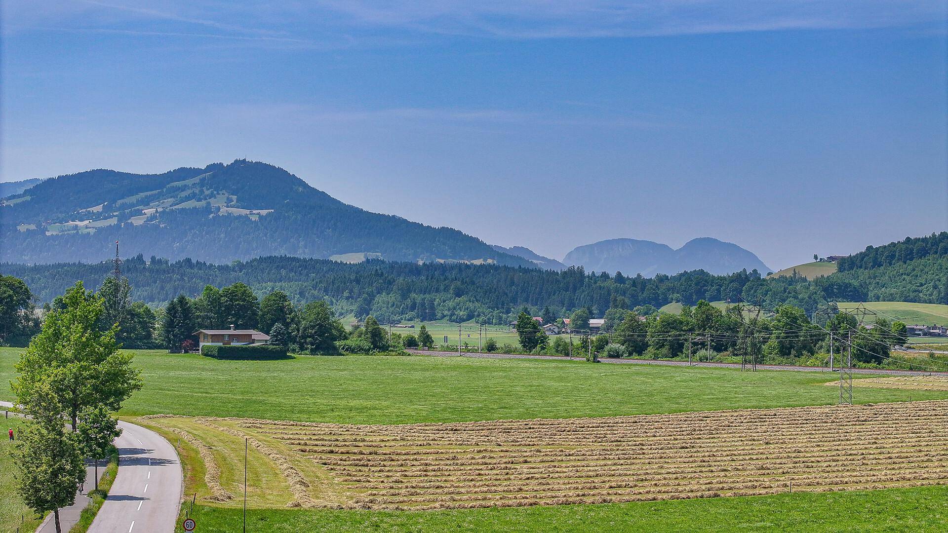 Weitläufige grüne Felder und sanfte Hügel prägen die idyllische Landschaft.
