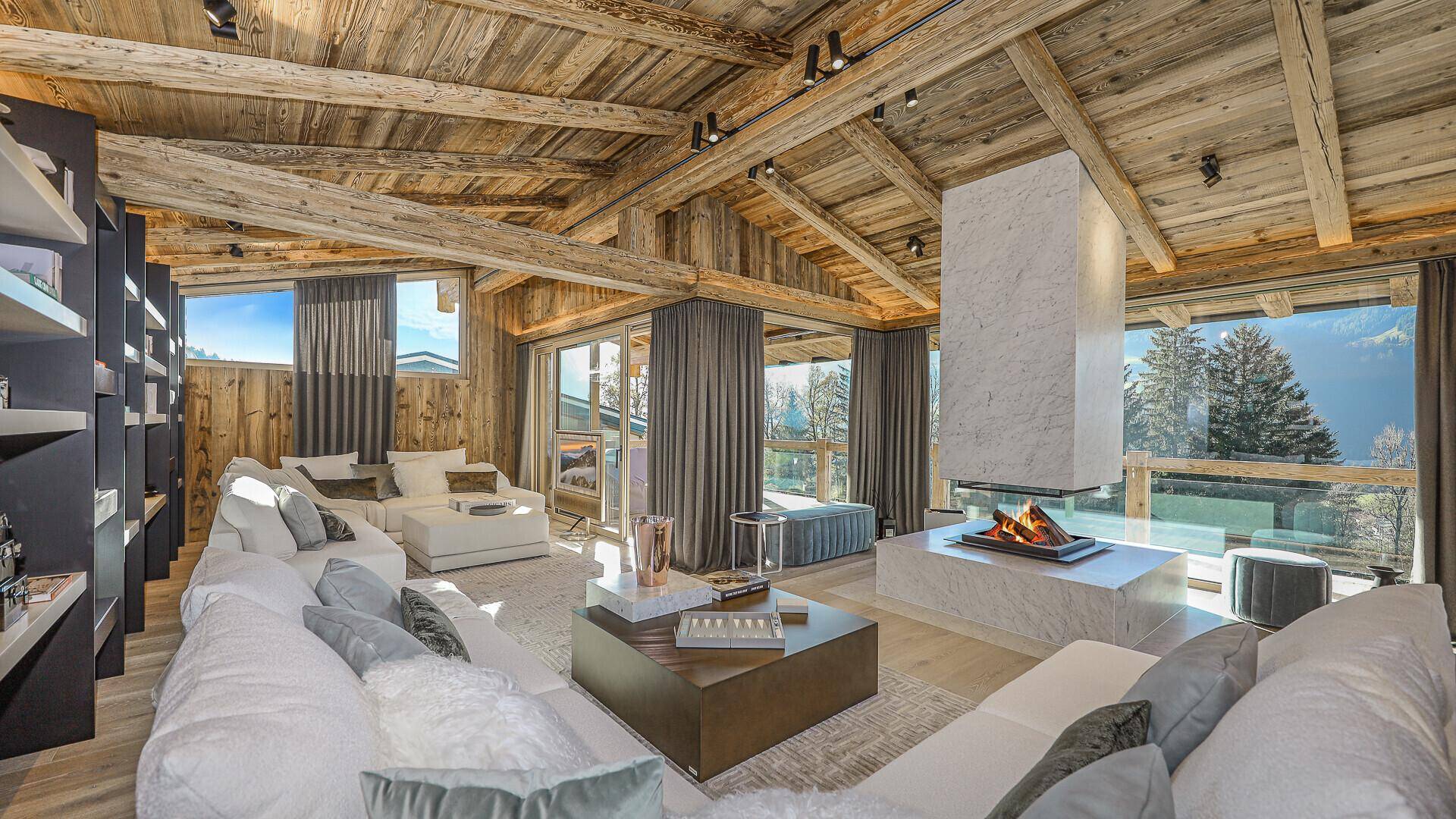 Gemütliches Wohnzimmer im alpinen Stil mit Holzbalkendecke, Kamin und bequemen Sofas.