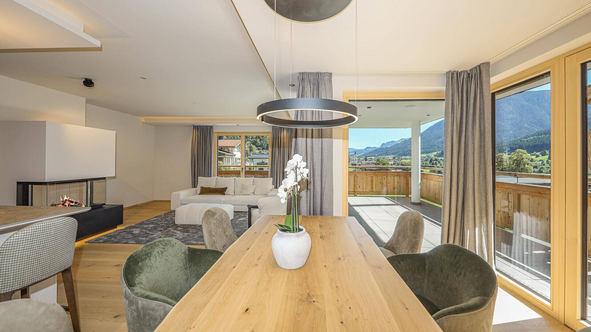 Heller Essbereich mit großem Holztisch, modernen Stühlen und Panoramablick auf die Berge.