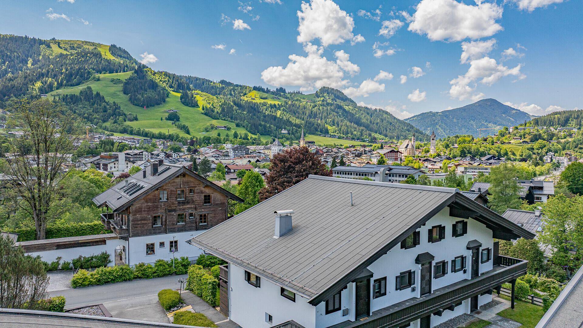 Panoramablick auf die Stadt und die umliegende Berglandschaft unter blauem Himmel.