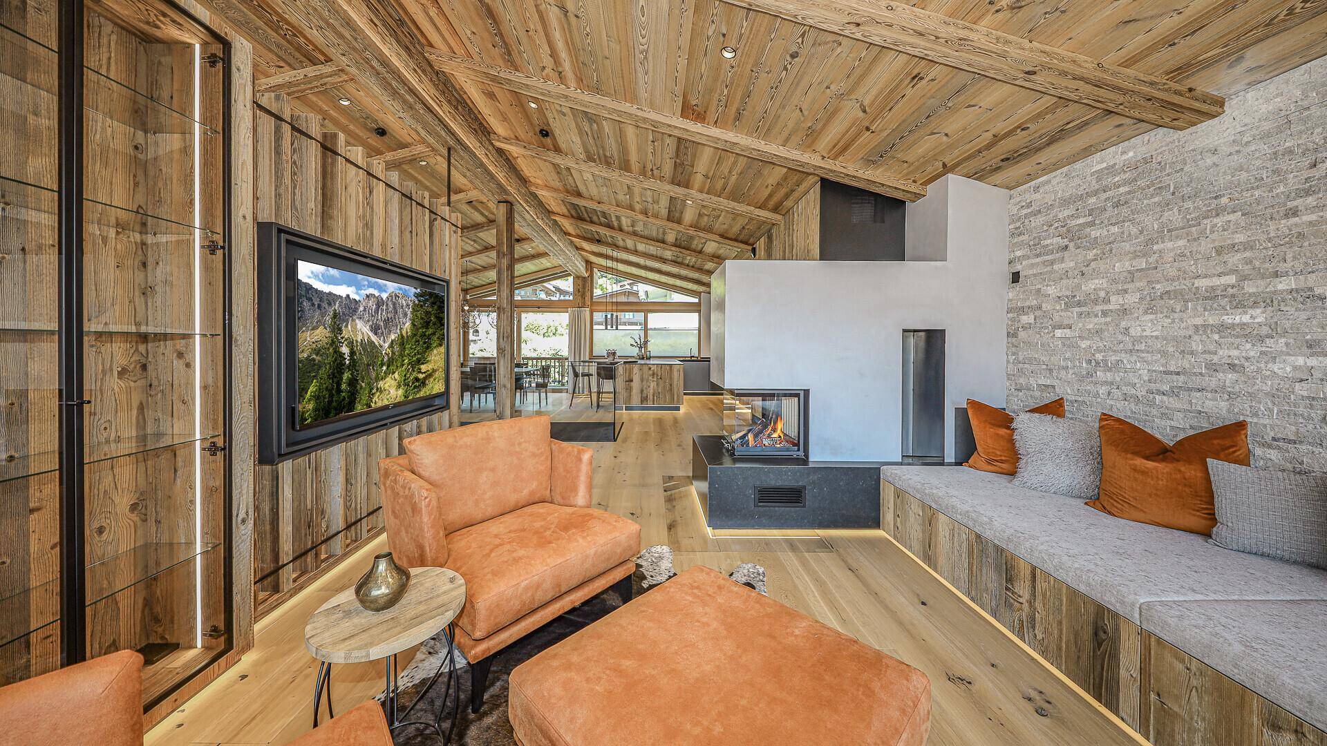Stilvolles Wohnzimmer mit Kamin, Holzwänden und bequemen Ledersesseln in warmen Farbtönen.