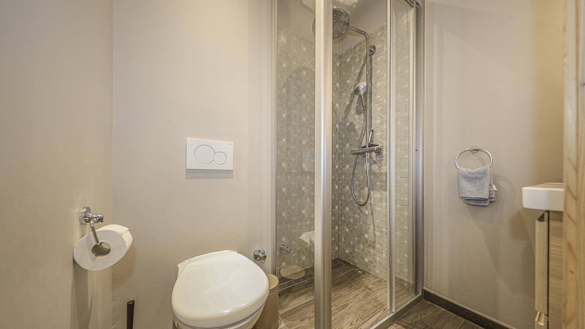 Kleines Badezimmer mit Dusche, WC und modernem Wand-WC in neutralen Farben.