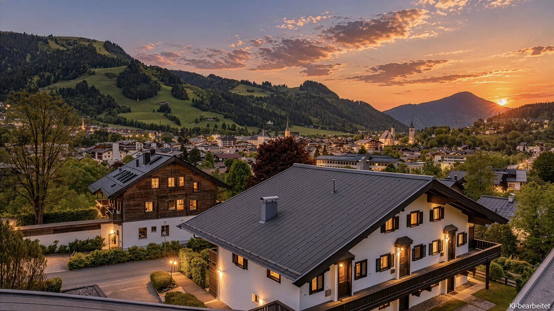 Malerische Abendstimmung über der Stadt mit beleuchteten Häusern und Bergen im Hintergrund.