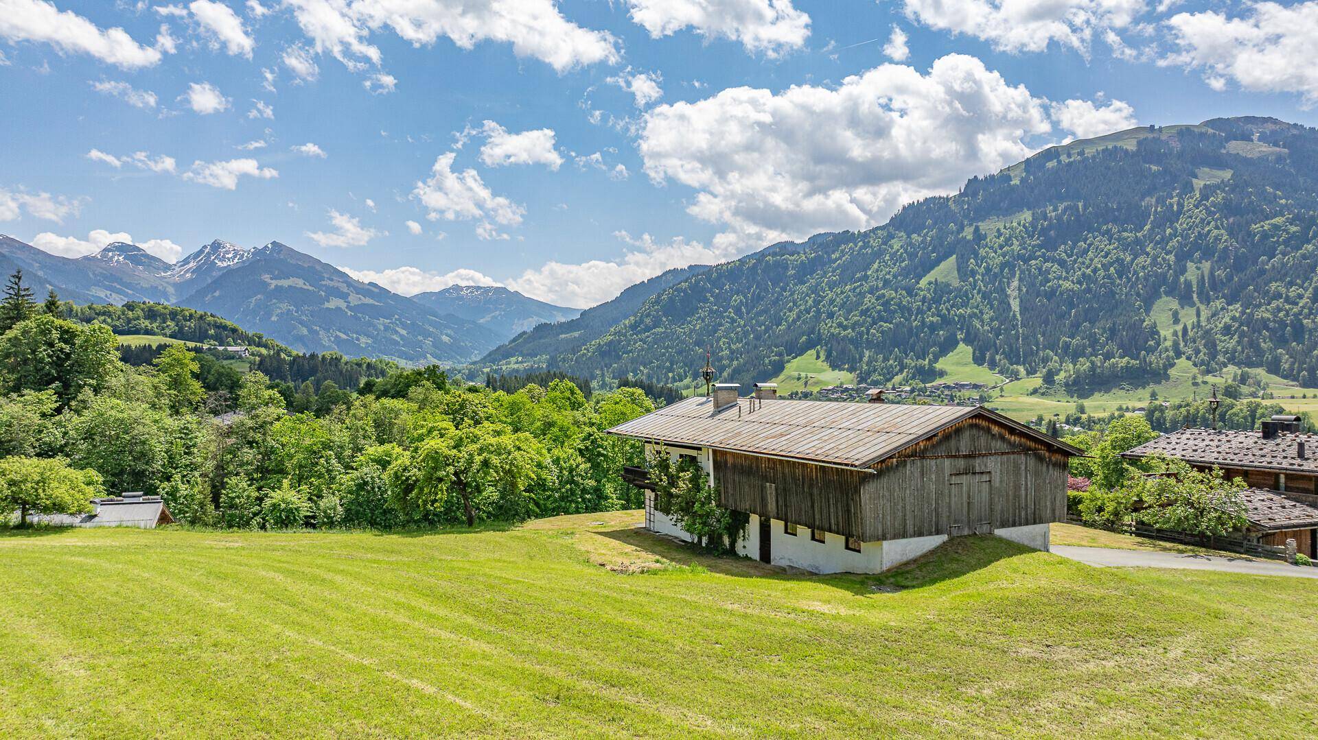 Ländliches Anwesen mit Holzfassade und weitem Blick auf die umliegende Bergwelt.