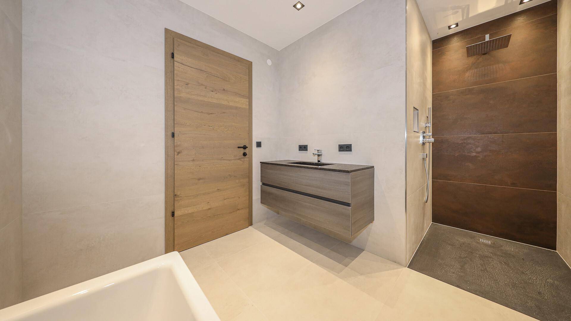 Modernes Badezimmer mit Badewanne, schwebendem Waschbecken und großer begehbarer Dusche.