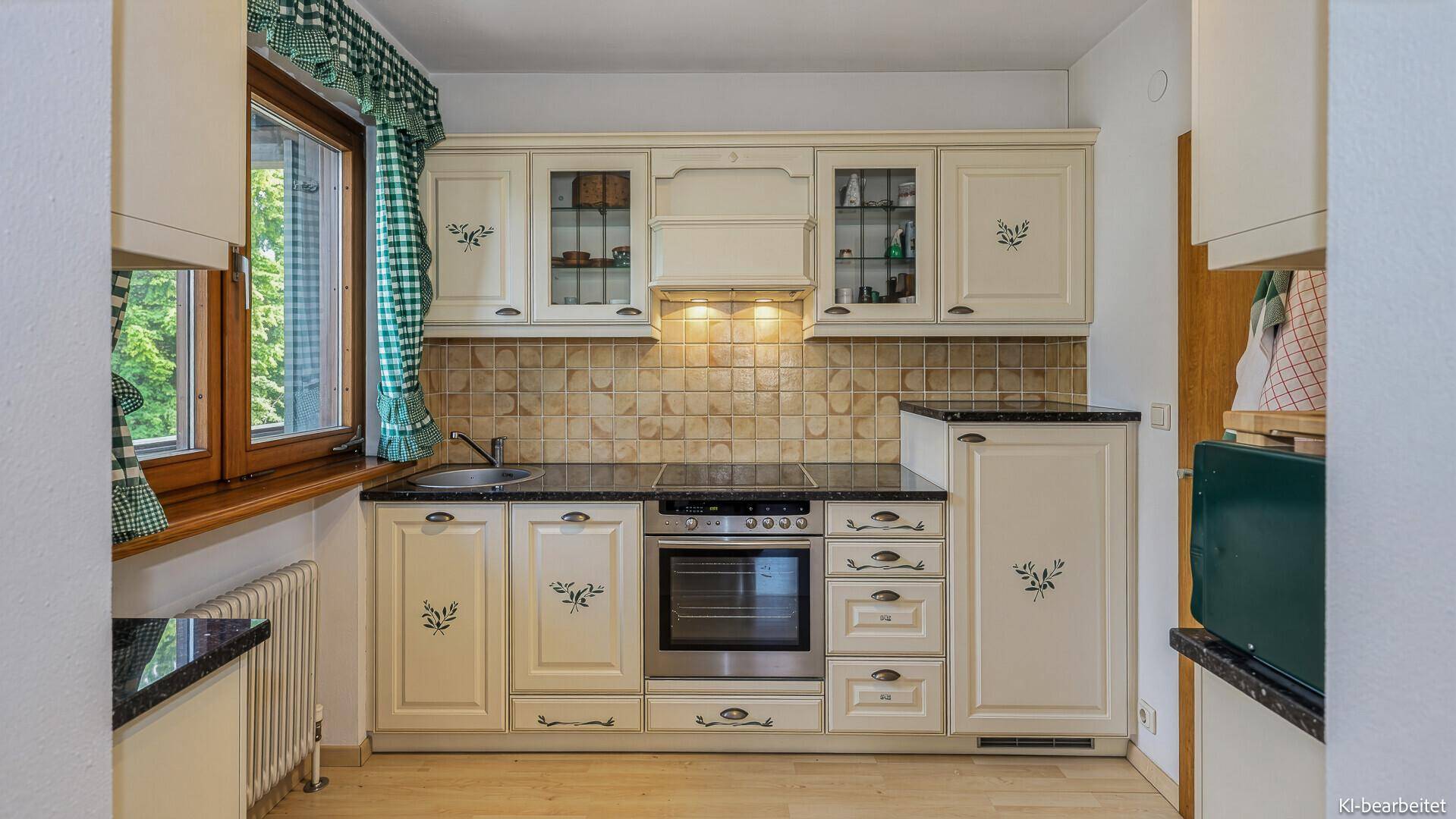 Traditionelle Küche mit cremefarbenen Schränken, dunkler Arbeitsplatte und Fensterblick.