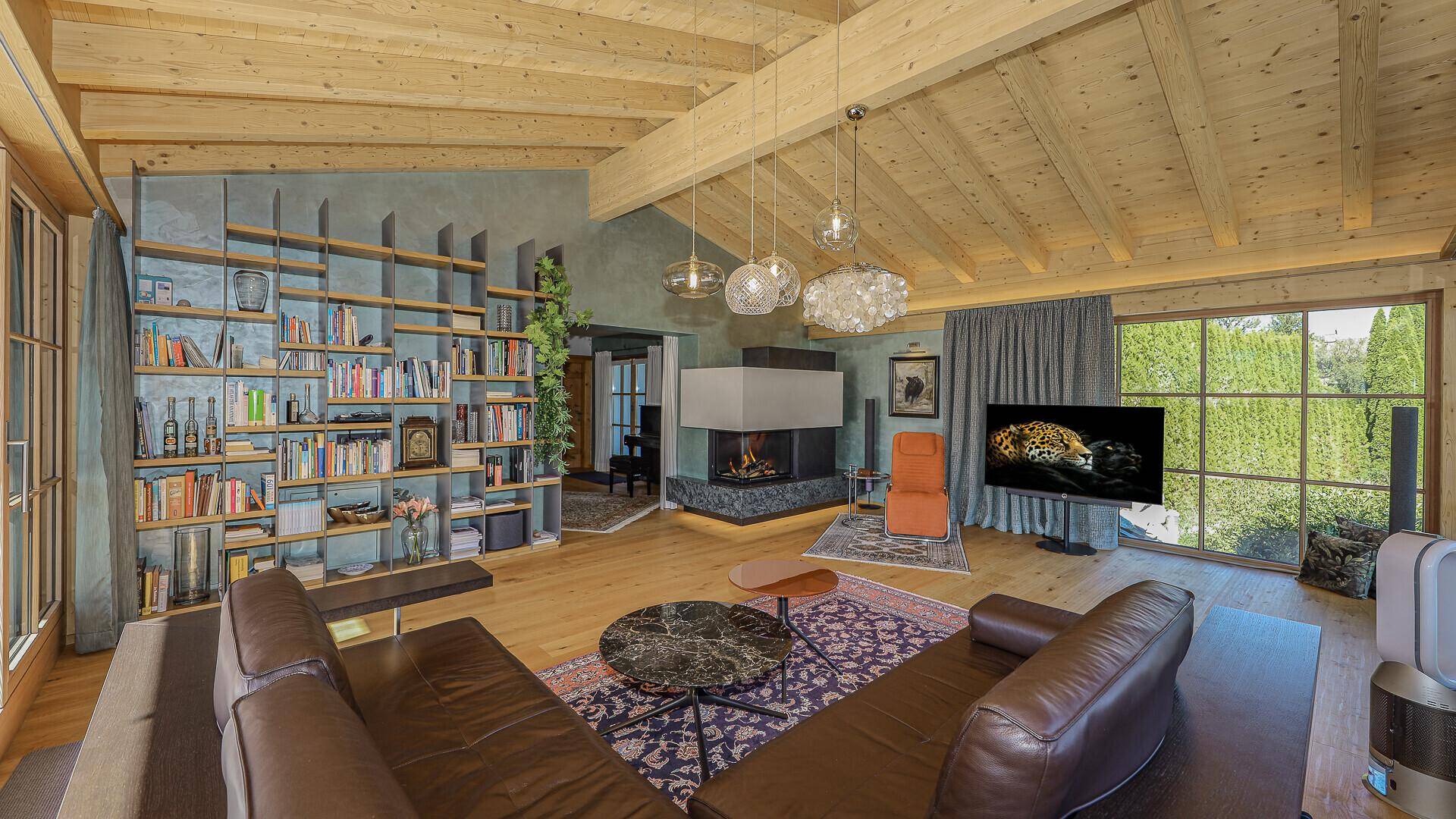 Gemütliches Wohnzimmer mit Kamin, Bücherregal und Holzbalkendecke, ideal zum Entspannen.