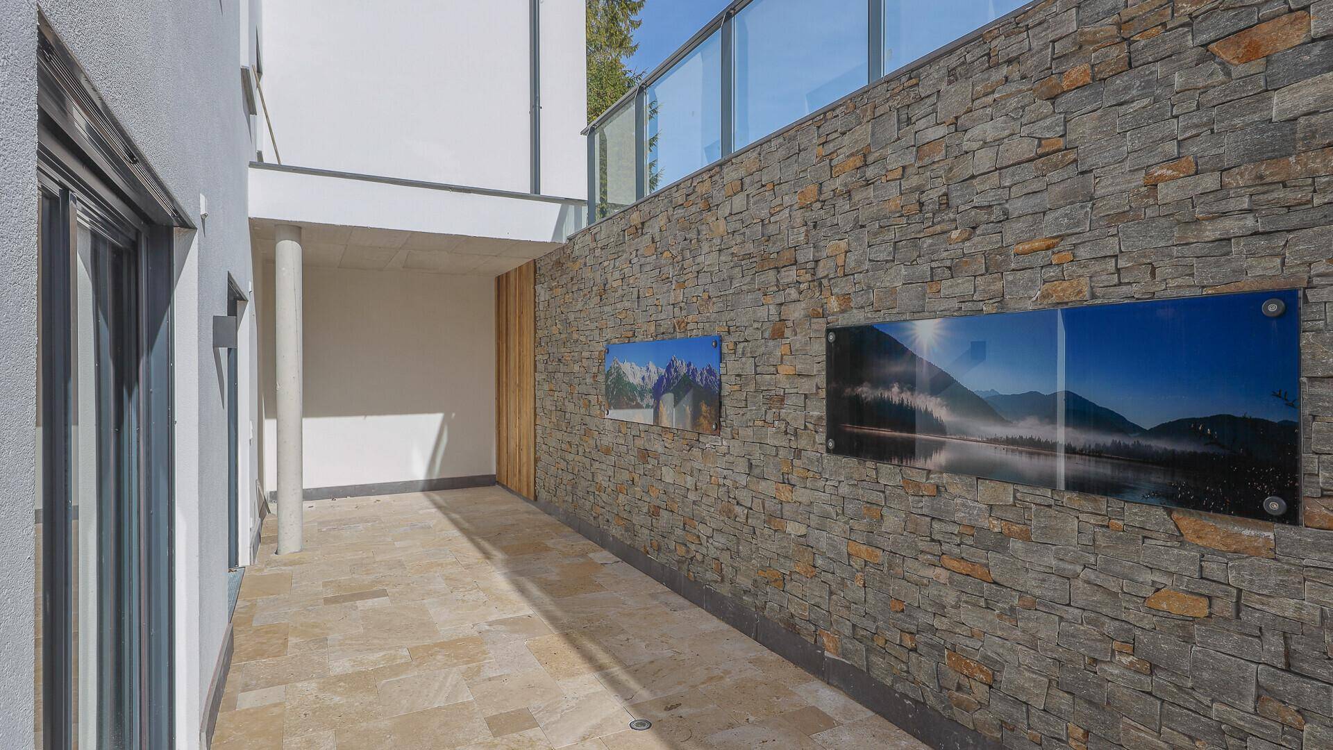 Geräumige Außenterrasse mit Natursteinwand, die viel Platz für individuelle Gestaltung bietet.