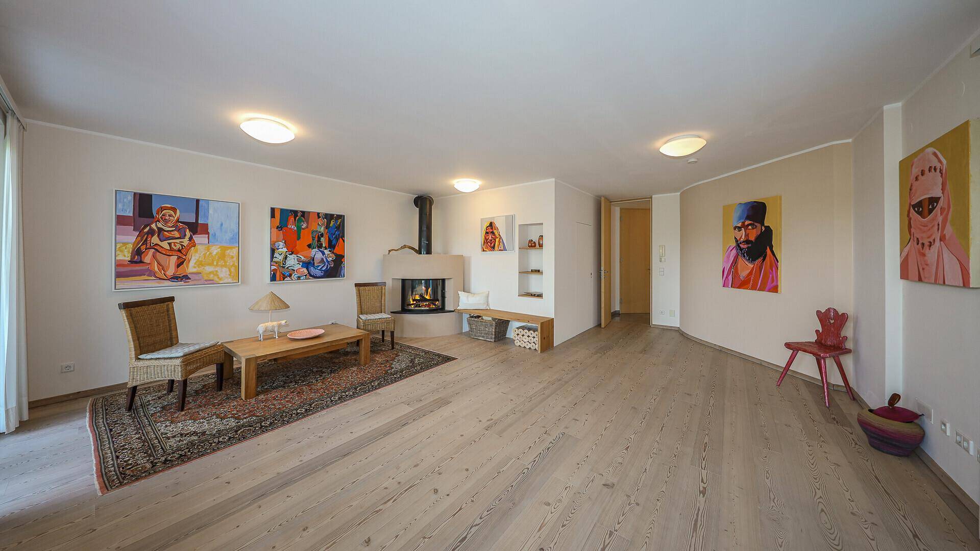 Geräumiges Wohnzimmer mit Holzboden, Kamin und farbenfrohen Kunstwerken, bietet eine gemütliche Atmosphäre.