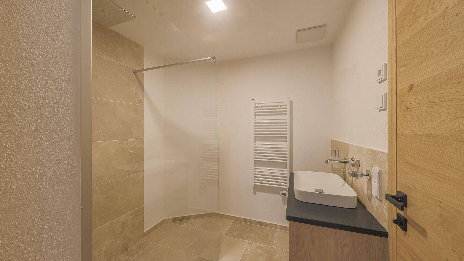 Modernes Badezimmer mit begehbarer Dusche, Waschbecken und beheiztem Handtuchhalter.