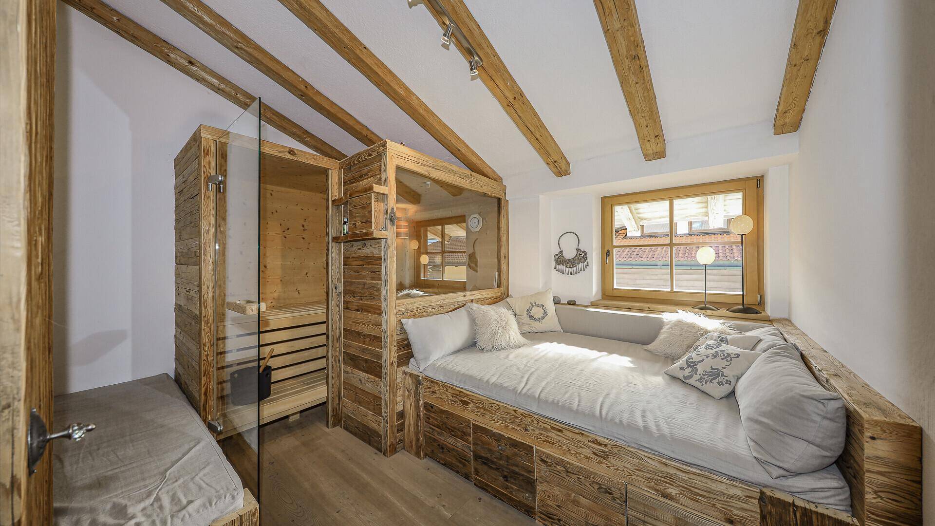 Gemütliches Schlafzimmer im alpinen Stil mit integrierter Sauna und sichtbaren Holzbalken.