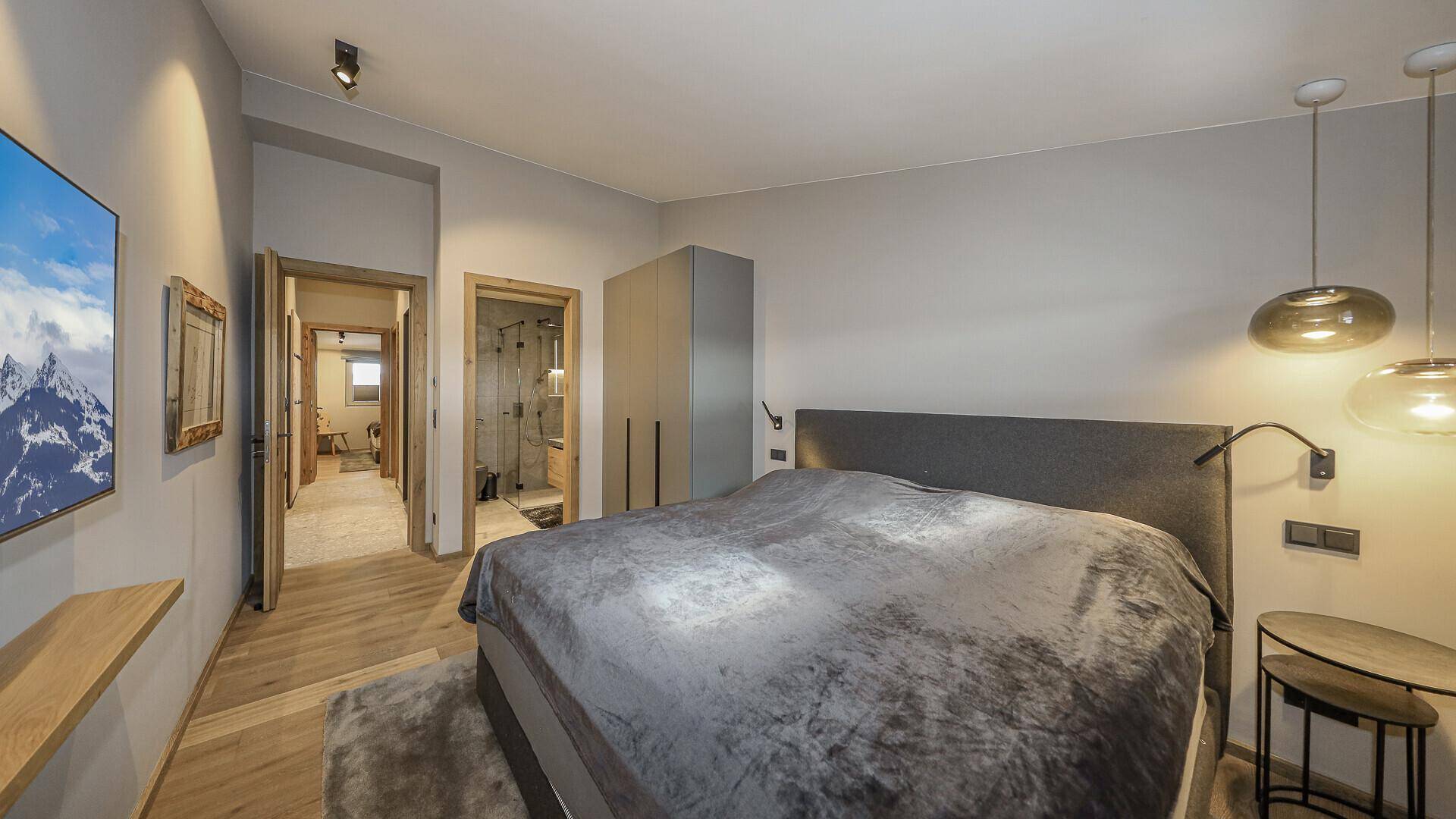 Schlafzimmer mit Doppelbett und direktem Zugang zu einem modernen Badezimmer.