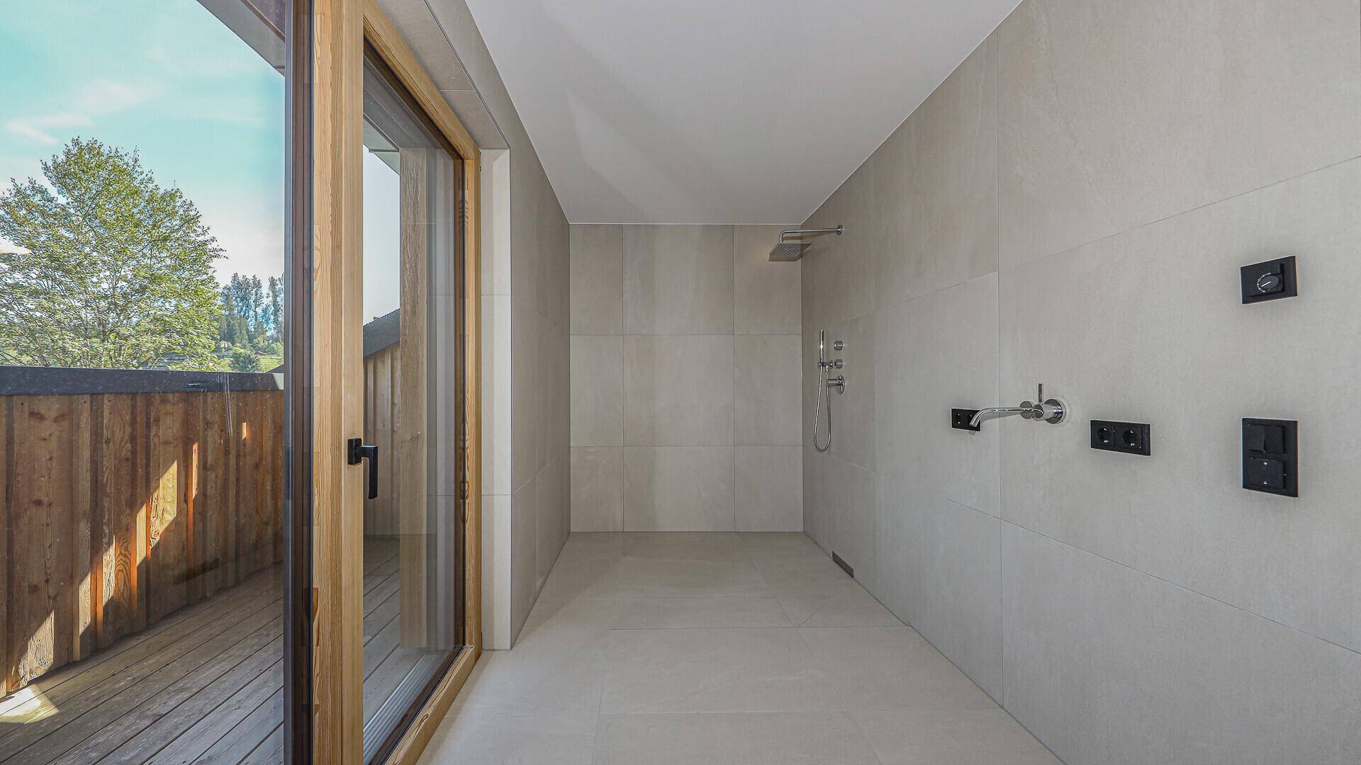 Modernes Badezimmer mit großformatigen Fliesen und einer geräumigen begehbaren Dusche.