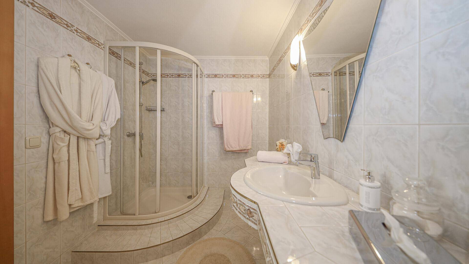 Helles Badezimmer mit Duschkabine, Waschbecken und Fliesen in traditionellem Stil.